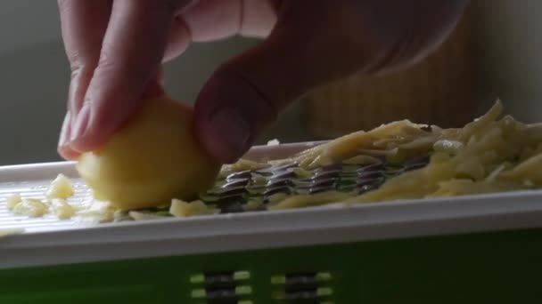 Mãos masculinas esfregando batatas em um ralador de cozinha para cozinhar alimentos vegetarianos — Vídeo de Stock