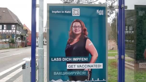 11 декабря 2021 - Кель, Германия: Плакат с призывом к вакцине против вируса Covid19 на автобусной остановке с надписью на немецком, английском и русском языках. Превентивная борьба с вирусом гриппа — стоковое видео