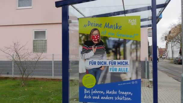 11 december 2021 - Kehl, Duitsland: Een affiche bij een bushalte voor een masker tegen COVID19, de inscriptie in het Duits. Preventie van de bestrijding van het influenza-coronavirus — Stockvideo