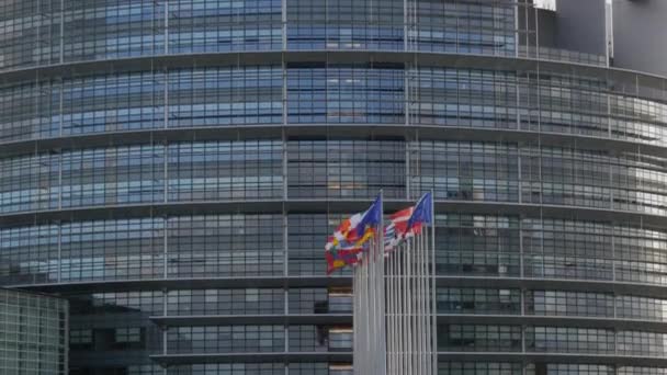 7 december 2021 - Straatsburg, Frankrijk: gebouw van het Europees Parlement. Vlaggen van Europese landen die zwaaien met het hoofdkwartier van het Europees Parlement op de achtergrond zijn onder meer het Verenigd Koninkrijk — Stockvideo