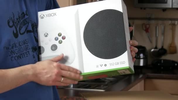 9 Grudzień, 2021 - Kehl, Niemcy: Człowiek szczęśliwie głaszcze pudełko z Xbox w domu. Domowa konsola do gier wideo stworzona przez Microsoft. — Wideo stockowe