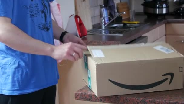 9 de dezembro de 2021 - Kehl, Alemanha: Um homem desempacota uma grande parcela de mercadorias entregues. Caixa da loja online Amazon — Vídeo de Stock