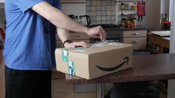9 de diciembre de 2021 - Kehl, Alemania: Un hombre desempaca una gran parcela de mercancías entregadas. Caja de la tienda online de Amazon — Vídeos de Stock