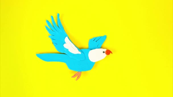 Uccello plastilina in volo con la tecnica dello stop motion. Uccello dei cartoni animati divertente sbatte le ali creando l'illusione di volo su uno sfondo giallo — Video Stock