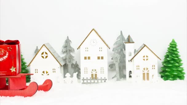 Kehl, Almanya - 29 Kasım 2021: Kar kaplı ahşap bir kasabanın arka planına komik bir şekilde kızaktan düşen güzel kırmızı bir çikolata kutusu. Stop-motion animasyonu — Stok video