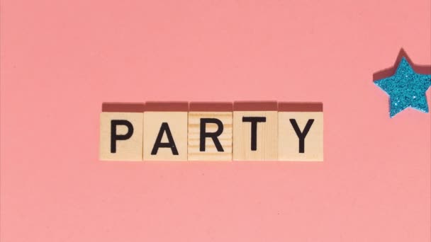 Stop motion animation of wooden letters with the word party add up. Festive multicolored stars on a gentle coral background — Wideo stockowe