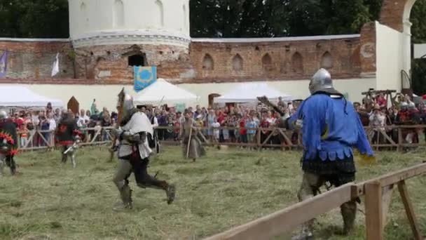Trostyanets, Ukrajina - 21. srpna 2021: Diváci se zájmem sledují reprodukce středověké bitvy. Lidé v rytířské zbroji a kovových helmách a štítech bojují studenou ocelí — Stock video