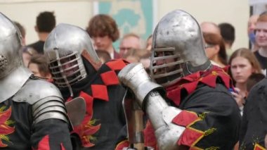 Trostyanetler, Ukrayna - 21 Ağustos 2021: Seyirciler ortaçağ savaşlarının çoğalmasına ilgi gösteriyorlar. Şövalye zırhı ve metal miğferler ve kalkanlar giymiş insanlar soğuk çelikle savaşıyor.