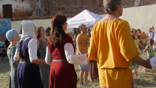 Trostyanets, Ukrajina - 21. srpna 2021: Středověké tance. Lidé tančí ve velkém kruhu v krásných středověkých šatech vedle moderních kostýmů — Stock video