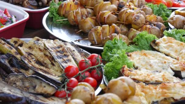 Bohatě prostřený stůl s klobásami, grilovanou zeleninou, paprikou, cuketou, lilkem, bramborami. Slavnost pouličních jídel, tučné jídlo, fast food — Stock video