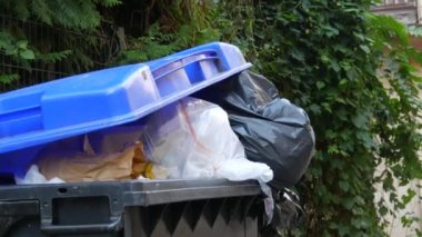 Sokakta içi çöp dolu mavi çöp tenekesi. Çevre kirliliği sorunu