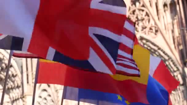 在法国斯特拉斯堡大教堂的背景下，一排意大利、法国、西班牙、欧盟的欧洲和美国国旗 — 图库视频影像