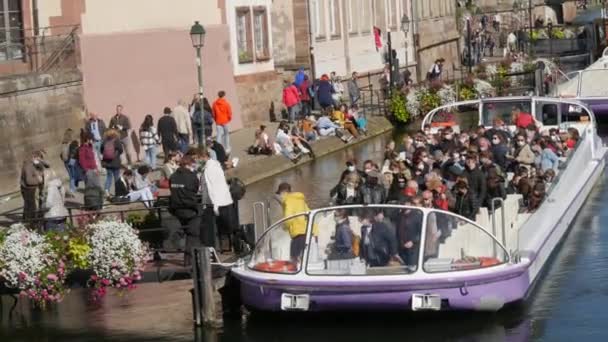 10 октября 2021 года - Страсбург, Франция: Туристическая водная лодка на реке Иль со многими туристами на борту в защитных медицинских масках против ковида-19. Лодка причаливает к берегу — стоковое видео