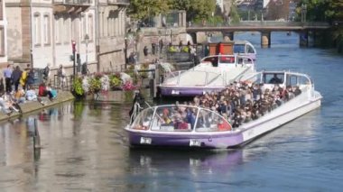 10 Ekim 2021 - Strasbourg, Fransa: Ile Nehri 'nde turist su teknesi ve içinde kovid-19' a karşı koruyucu tıbbi maskeler takan birçok turist var. Gemi kıyıya vuruyor.