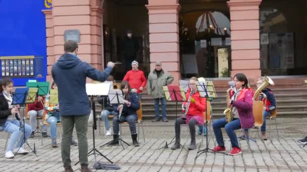 Gengenbach, Duitsland - 15 december 2021: Kinderorkest bespeelt verschillende muziekinstrumenten op straat, voor het gebouw, luisterend naar de hoofdonderwijzer — Stockvideo