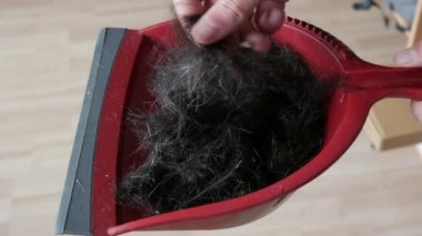 Kırmızı kepçeyle kesilmiş bir sürü erkek saçı var. Adam elleriyle yeni kesilmiş saçına dokunuyor.