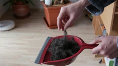 Kırmızı kepçeyle kesilmiş bir sürü erkek saçı var. Adam elleriyle yeni kesilmiş saçına dokunuyor.