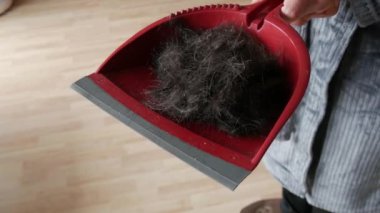 Elinde bir sürü erkek olan bir adam kırmızı bir kepçeyle kafasından kesilmiş bir sürü siyah saç.