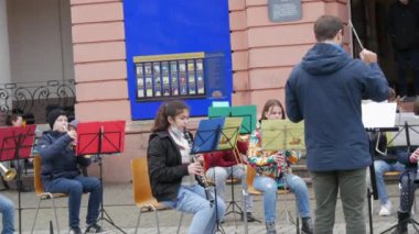 Gengenbach, Almanya - 15 Aralık 2021: Çocuk orkestrası sokakta, binanın önünde farklı müzik aletleri çalıyor, ana hocayı dinliyor
