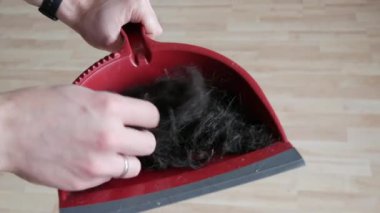 Kırmızı kepçeyle kesilmiş bir sürü erkek saçı var. Adam elleriyle yeni kesilmiş saçına dokunuyor.