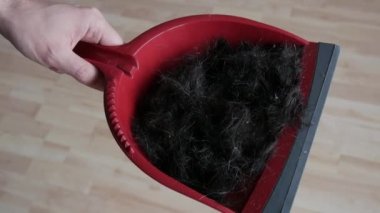 Elinde bir sürü erkek olan bir adam kırmızı bir kepçeyle kafasından kesilmiş bir sürü siyah saç.