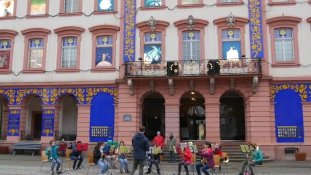 Gengenbach, Alemania - 15 de diciembre de 2021: Orquesta infantil tocando diferentes instrumentos musicales en la calle, frente al edificio, escuchando al maestro principal — Vídeo de stock