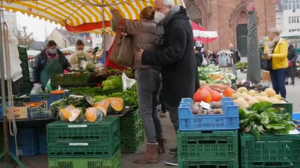 Kehl, Németország - november 19, 2021: Az emberek végigsétálnak az élelmiszerpiacon, kiválasztják a termékeiket. Sok zöldség és gyümölcs van a pulton. Orvosi maszkban és anélkül élő emberek. — Stock videók