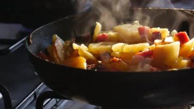 Kızartma tavası ve sıcak pişmiş yemek. Kızarmış patates ve sosis sıcak buharın üzerinde pişiyor. Ağır kızartma, fast food.