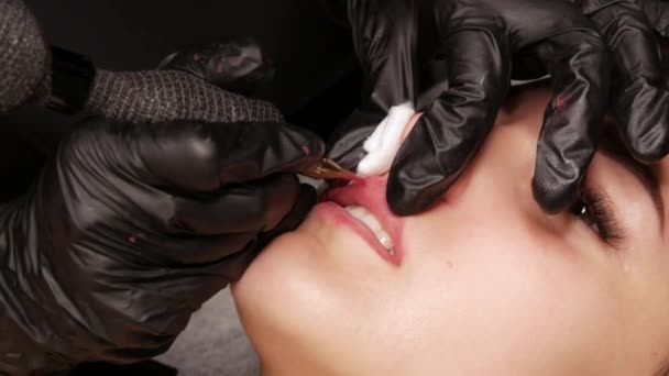 Mikroblading tetování na rty se speciálním barvivem červený pigment, který opravuje barvu rtů v kosmetické klinice. Trvalé make-up rty postup nanášení pigment make-up na rty s tetovacím strojem zblízka — Stock video