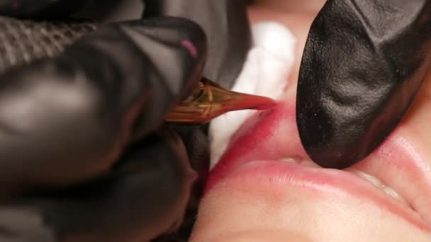 Tatouage à lèvres Microblading avec un pigment rouge à coloration spécial qui corrige la couleur des lèvres dans la clinique de cosmétologie. Procédure permanente de maquillage des lèvres appliquant un maquillage pigmentaire sur les lèvres avec une machine à tatouer gros plan — Video