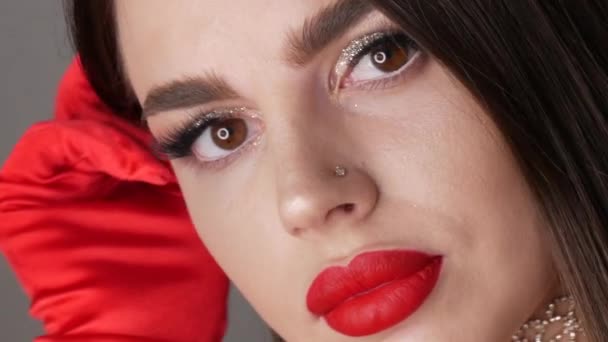 Hermosa modelo de niña con labios grandes pintados con lápiz labial rojo. Mujer joven posando con elegantes guantes rojos y maquillaje de noche brillante, mirando a la cámara — Vídeos de Stock