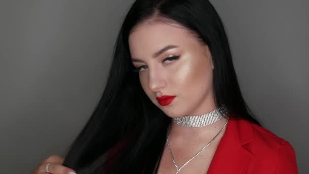 Gadis cantik dengan bibir besar dicat dengan lipstik merah. Wanita muda berpose dalam gaya merah Blazer kalung terbuat dari rhinestones dan make-up malam yang cerah, melihat kamera — Stok Video