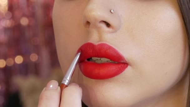 Maquillaje labial brillante, grandes labios hermosos están pintados con lápiz labial rojo con un cepillo especial en un salón de belleza. Maquillaje profesional vista de cerca — Vídeos de Stock