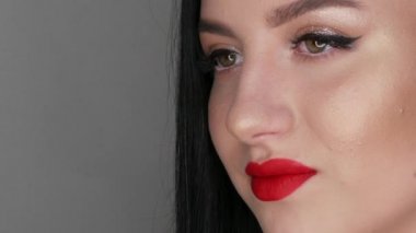 Büyük dudakları kırmızı rujla boyanmış güzel kız modelin yakın görüntüsü. Parlak makyajlı genç bir kadın.