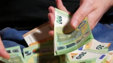Bir adam 50 ve 100 Euro 'luk banknotlar sayıyor. İşadamı, avroluk banknotları sayıyor. Para kazanan, ekonomi konsepti, Avro para birimi faturaları. Para nakit, mali hesaplamalar. Kapat.