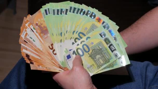 男は50と100ユーロの紙幣のファンをカウントします。ビジネスマンはユーロ紙幣を数える。お金の勝者、経済概念、ユーロ通貨の請求書。お金の現金財務計算。閉じろ! — ストック動画