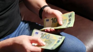 Bir adam 50 ve 100 Euro 'luk banknotlar sayıyor. İşadamı, avroluk banknotları sayıyor. Para kazanan, ekonomi konsepti, Avro para birimi faturaları. Para nakit, mali hesaplamalar. Kapat.