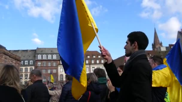 Strasburg, Francja - 26 lutego 2022: Ludzie z ukraińskimi flagami i plakatami protestują przeciwko wojnie na Ukrainie. Demonstracja przeciwko wojnie między Ukrainą a Rosją. Protesty przeciwko Putinowi — Wideo stockowe
