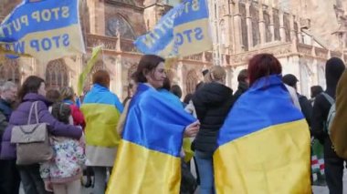 Strasbourg, Fransa - 26 Mart 2022: Rusya ile savaşa karşı Ukrayna 'yı destekleyen gösteri. Bayraklı ve ulusal kostümlü insanlarda savaş karşıtı posterler var.