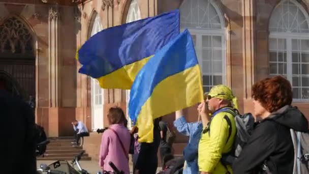 法国斯特拉斯堡- 2022年3月26日：支持乌克兰反对与俄罗斯战争的示威。拿着国旗、身穿民族服装的人拿着反战海报 — 图库视频影像