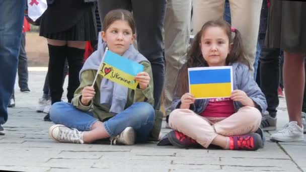 Strasburg, Francja - 26 marca 2022 r.: Demonstracja na rzecz Ukrainy przeciwko wojnie z Rosją. Dzieci na ziemi z flagami trzymają plakaty antywojenne — Wideo stockowe