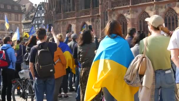 Страсбург, Франция - 26 марта 2022 года: Демонстрация в поддержку Украины против войны с Россией. Люди с флагами и в национальных костюмах держат антивоенные плакаты — стоковое видео