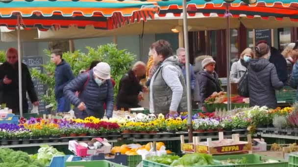 Kehl, Germany - October 29, 2021: People came to the local agricultural market to buy various farm products. Some visitors wear medical masks, others do not — ストック動画