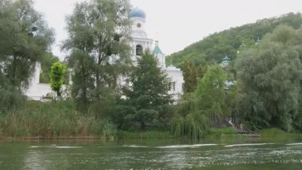 Wandel langs de groene rivier aan de oevers waarvan prachtige dichte bomen groeien. Uitzicht vanaf een plezierboot in beweging. Svyatogorsk Lavra, regio Donetsk, Oekraïne — Stockvideo