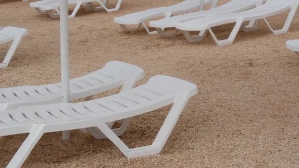 Tomma vita plastsolstolar på stranden. Strandsemester utan människor. — Stockvideo