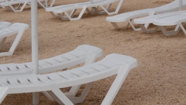 Άδειο λευκό πλαστικό ξαπλώστρες στην παραλία. Διακοπές στην παραλία χωρίς ανθρώπους. — Αρχείο Βίντεο