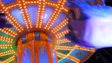 Ziyaretçilerin bindiği atlıkarınca. Akşamları, renkli ışıklarla dolu bir eğlence parkı. Aydınlatılmış atlıkarınca dolaşır