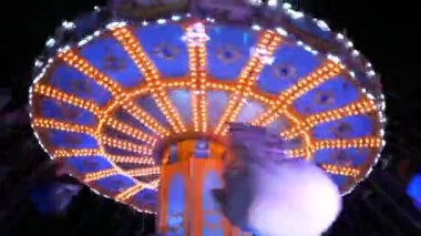 Ziyaretçilerin bindiği atlıkarınca. Akşamları, renkli ışıklarla dolu bir eğlence parkı. Aydınlatılmış atlıkarınca dolaşır