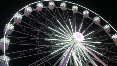 Beyaz büyük dönme dolap gece gökyüzünün arka planında dönüyor. Gece aydınlatmalı dönme dolap. Yanan Dönme dolap inşaatı