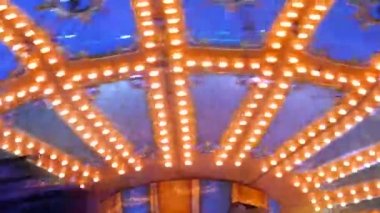 Ziyaretçilerin bindiği atlıkarınca. Akşamları, renkli ışıklarla dolu bir eğlence parkı. Aydınlatılmış atlıkarınca dolaşır